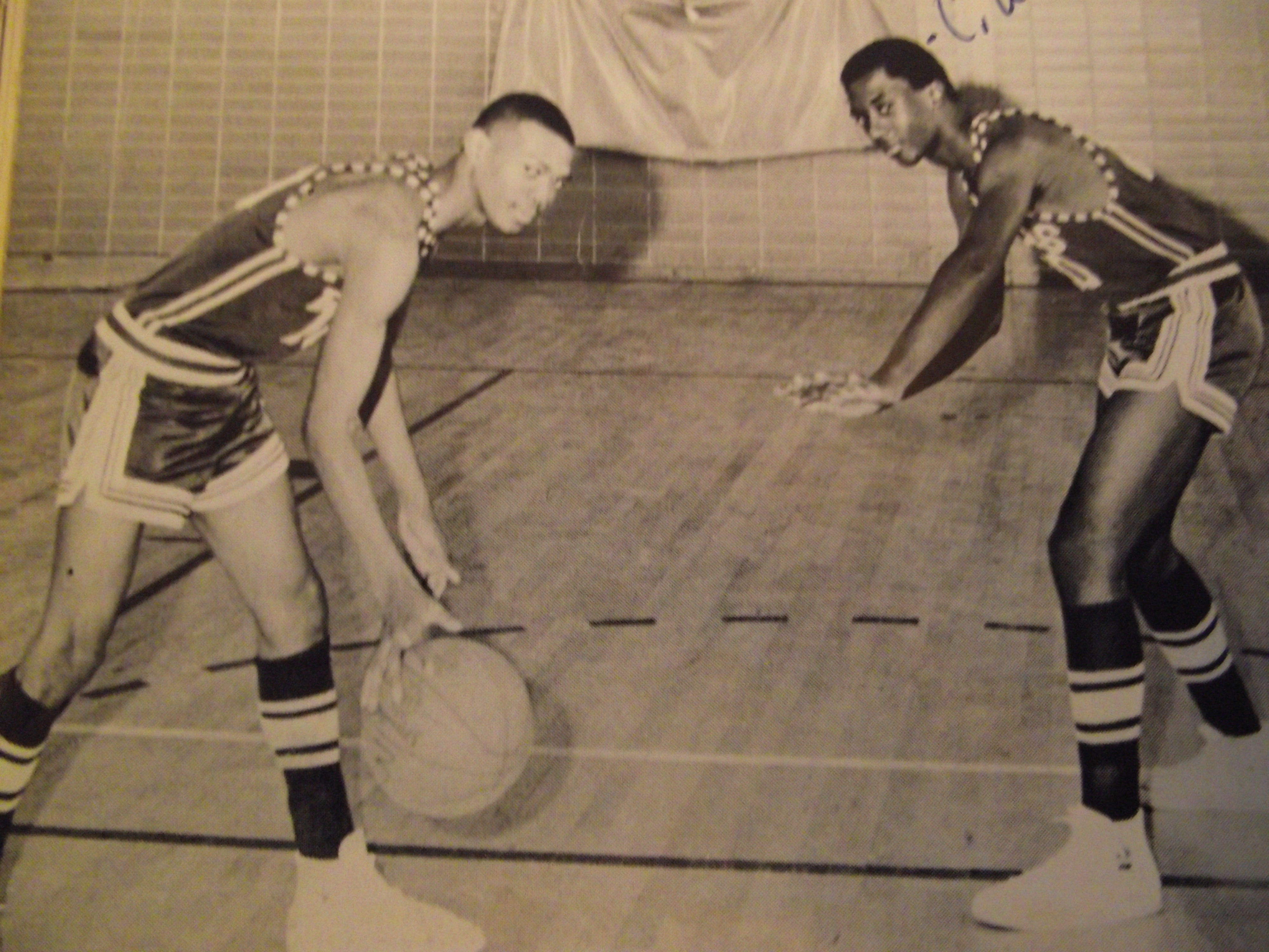 Two men are playing basketball on a court.