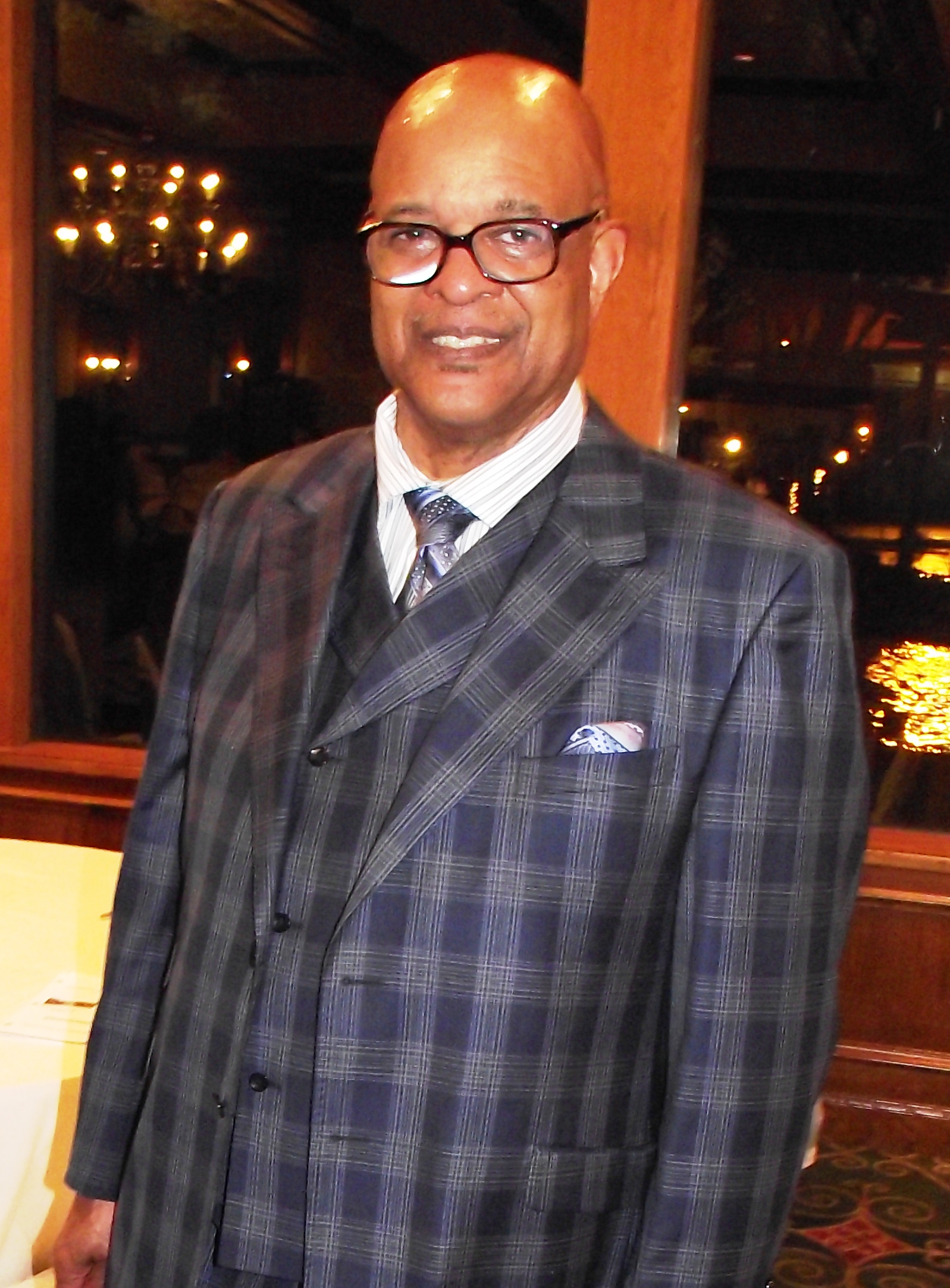 A man in a suit and tie standing next to a table.