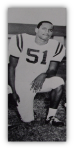 Football player in uniform kneeling on field.