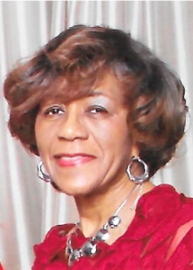 Smiling woman wearing red dress and jewelry.