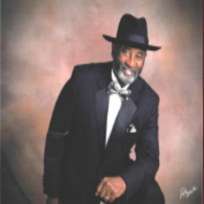 Man in suit and hat posing confidently.