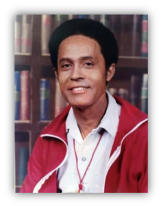 Smiling man in red jacket, bookshelf background.