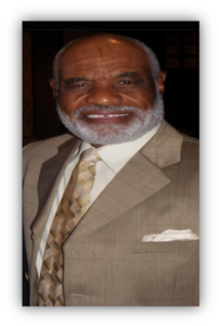 Smiling man in a beige suit.