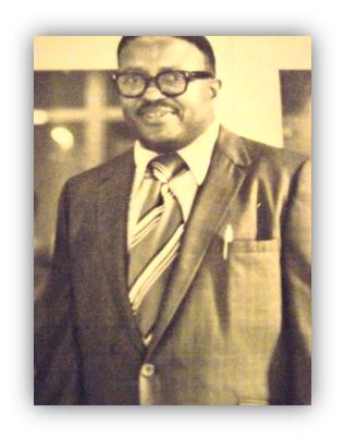 Man in suit with glasses, smiling warmly.