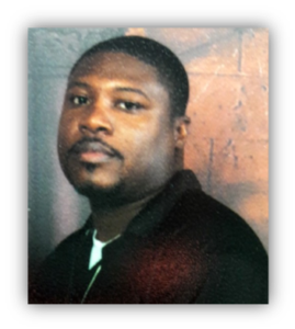 Man in dark shirt near brick wall.
