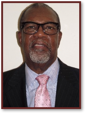 Man wearing glasses, suit, and pink tie.