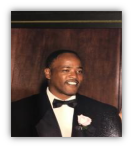 Man in tuxedo with a boutonniere smiling.