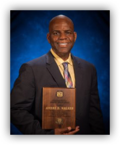 Man holding award plaque, wearing suit and tie.