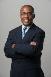 Smiling man in suit with crossed arms.