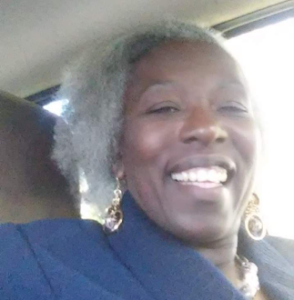 Smiling person with gray hair in car.
