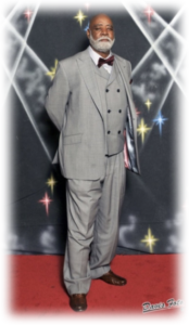 Man in gray suit on red carpet.