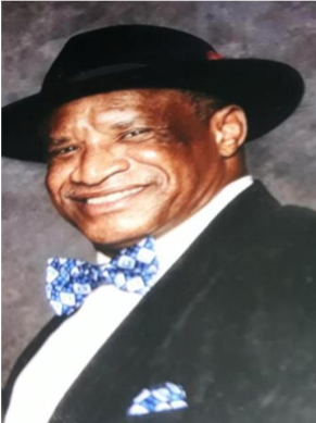 Man smiling, wearing hat and bow tie.