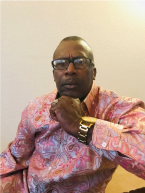 Man in pink patterned shirt, wearing glasses.