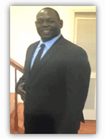 Man in suit smiling near staircase.