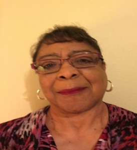 Elderly woman smiling with glasses and earrings.