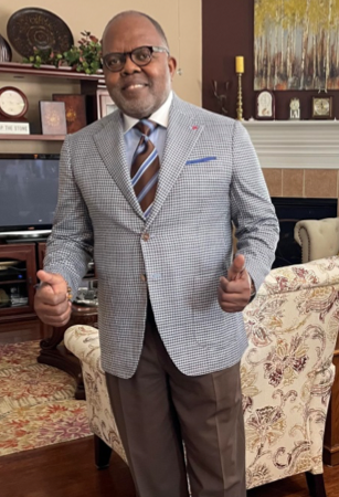 Man in suit giving thumbs up indoors.
