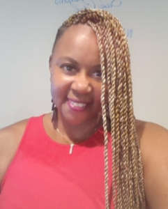 Smiling person in red top, braided hair.