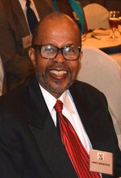 Smiling man in suit and red tie.