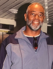 Smiling man wearing a jacket indoors.