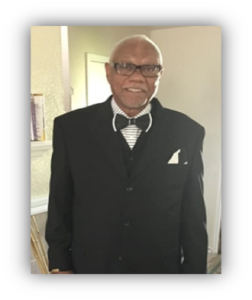 Elderly man in a suit smiling indoors.