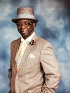 Man in suit and hat, blue background.