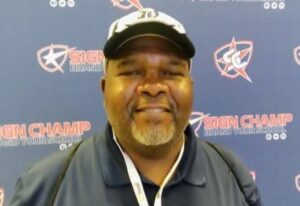 Man smiling in front of event backdrop.