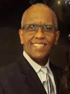 Smiling man wearing glasses and a suit.
