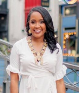 Smiling woman in white dress outside.