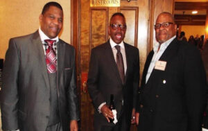 Three men in suits at an event.