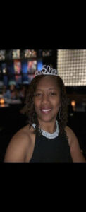 Woman wearing a tiara, smiling in restaurant.