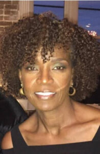 Smiling woman with curly hair and earrings.