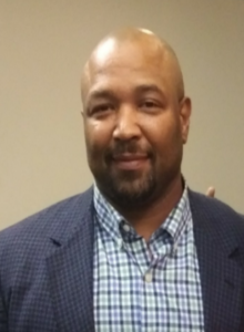 Man in checkered shirt and blue blazer.
