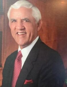 Smiling man in suit with red tie.